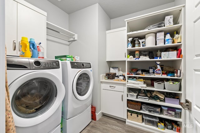 washroom with washer and clothes dryer, cabinets, and light hardwood / wood-style flooring