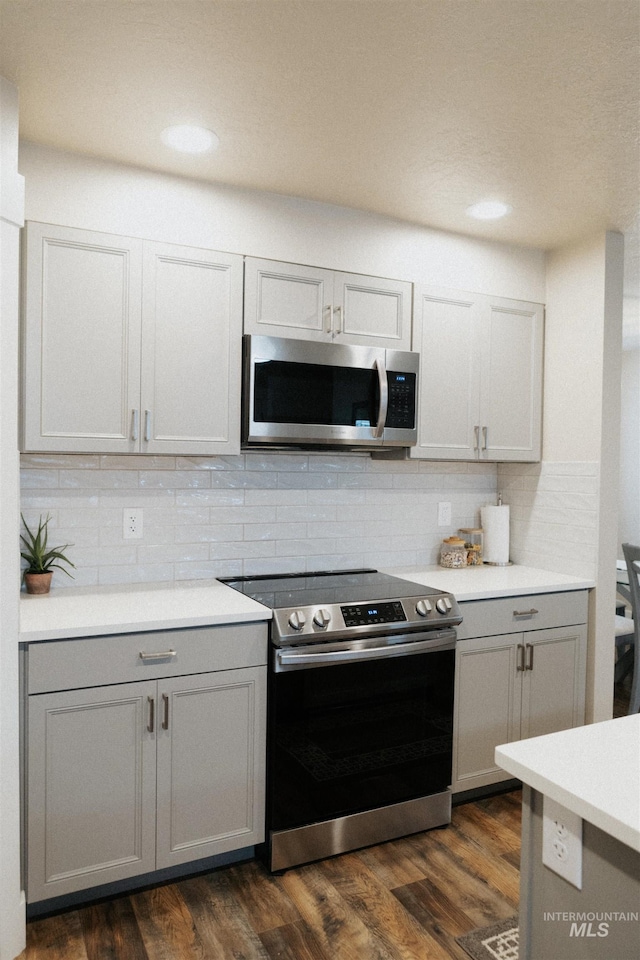 kitchen featuring appliances with stainless steel finishes, dark hardwood / wood-style flooring, and backsplash