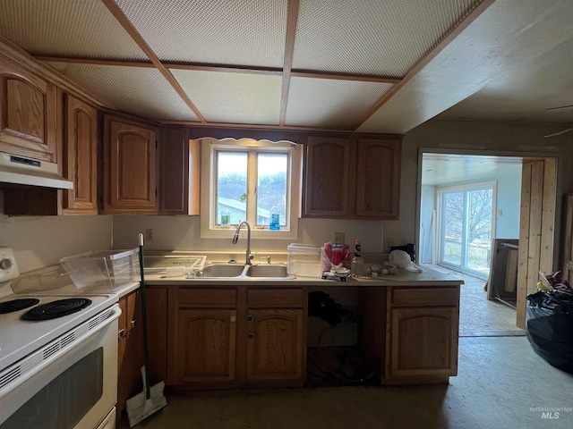 kitchen featuring light countertops, under cabinet range hood, a sink, and electric range