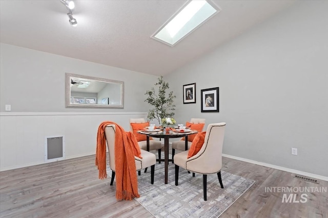 dining area featuring vaulted ceiling, wood finished floors, and visible vents