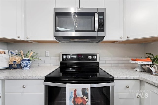 kitchen with appliances with stainless steel finishes, white cabinets, and light stone counters