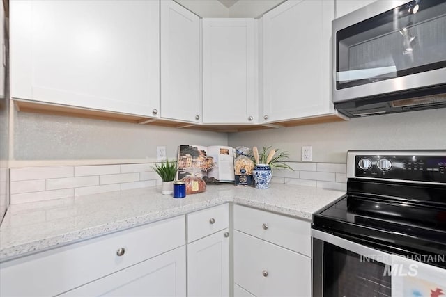 kitchen featuring appliances with stainless steel finishes, white cabinetry, and light stone countertops