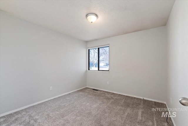 spare room featuring carpet, a textured ceiling, and baseboards