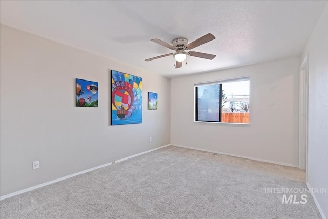 carpeted empty room featuring ceiling fan, a textured ceiling, and baseboards