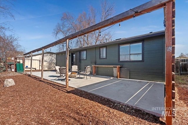 rear view of property featuring an outdoor fire pit, a patio, and fence