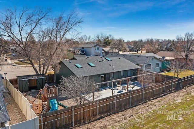 rear view of house with a fenced backyard, a residential view, a playground, and a patio