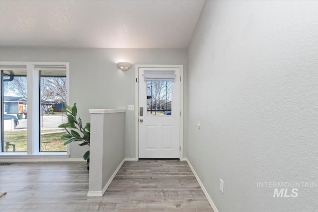 doorway with light wood-type flooring, plenty of natural light, and baseboards