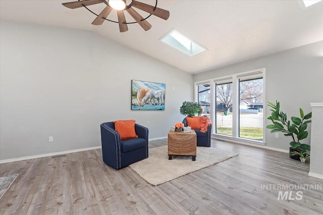 sitting room with lofted ceiling with skylight, a ceiling fan, baseboards, and wood finished floors