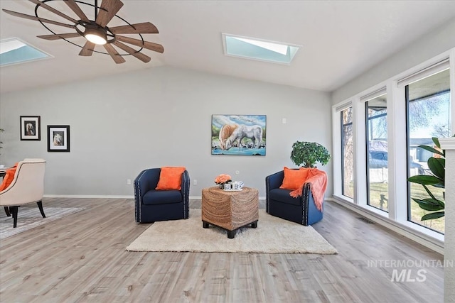 sitting room featuring vaulted ceiling with skylight, wood finished floors, visible vents, and baseboards