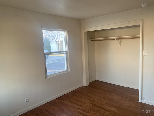 unfurnished bedroom featuring dark wood-type flooring and a closet