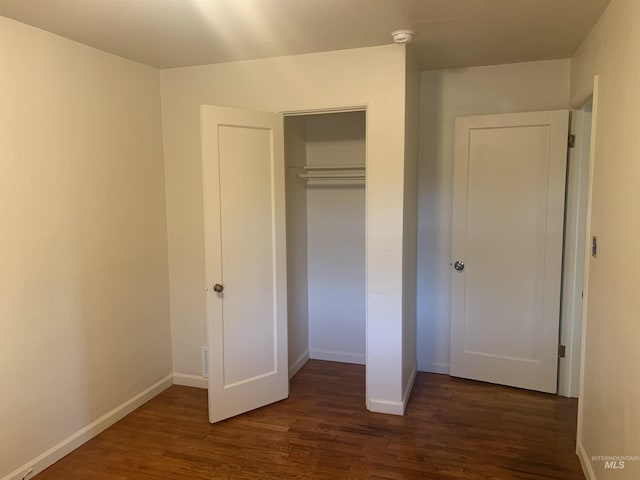 unfurnished bedroom featuring a closet and dark hardwood / wood-style flooring