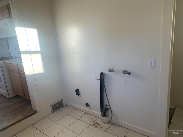 clothes washing area featuring washer / dryer and light tile patterned flooring