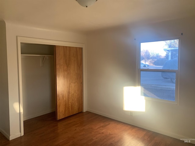 unfurnished bedroom with dark wood-type flooring and a closet