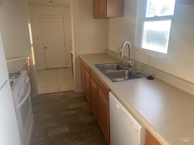 kitchen featuring white appliances, dark tile patterned floors, and sink