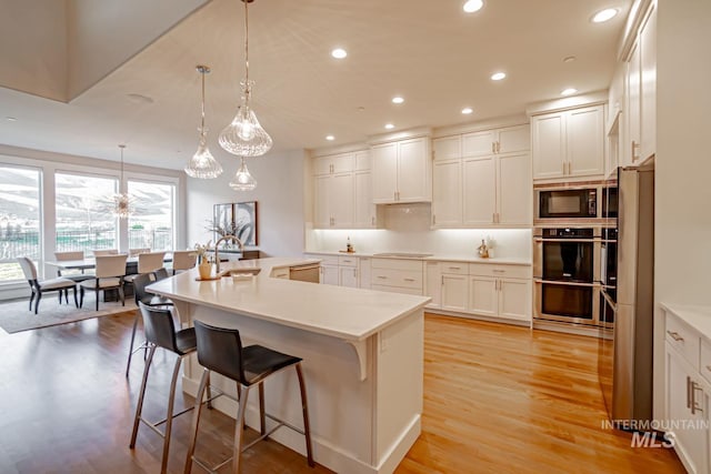 5946 E Barber Dr, Boise, ID 83716 - kitchen featuring recessed lighting, stainless steel appliances, light wood finished floors, a large island with sink, and a sink