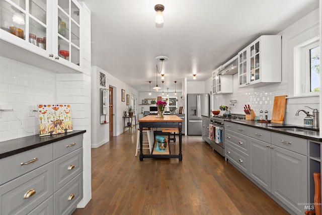 kitchen featuring backsplash, stainless steel appliances, dark countertops, and a sink