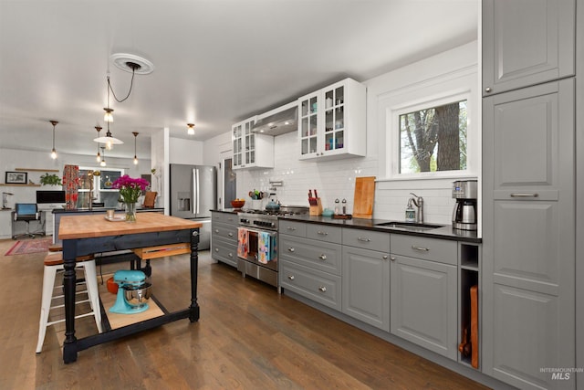 kitchen featuring dark countertops, a sink, gray cabinets, stainless steel appliances, and tasteful backsplash