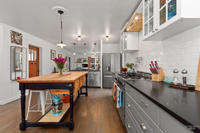 kitchen featuring decorative backsplash, dark wood finished floors, white cabinetry, wood counters, and stainless steel appliances