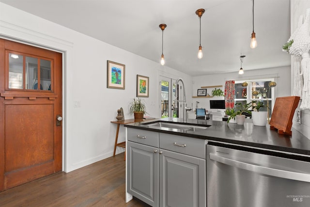 kitchen featuring dark countertops, dishwasher, a sink, baseboards, and dark wood-type flooring