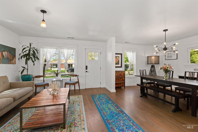 living room featuring an inviting chandelier, baseboards, wood finished floors, and visible vents