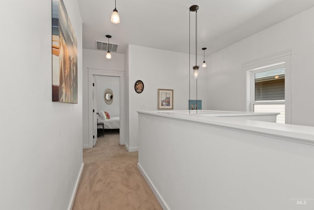 hallway with baseboards, light colored carpet, and visible vents