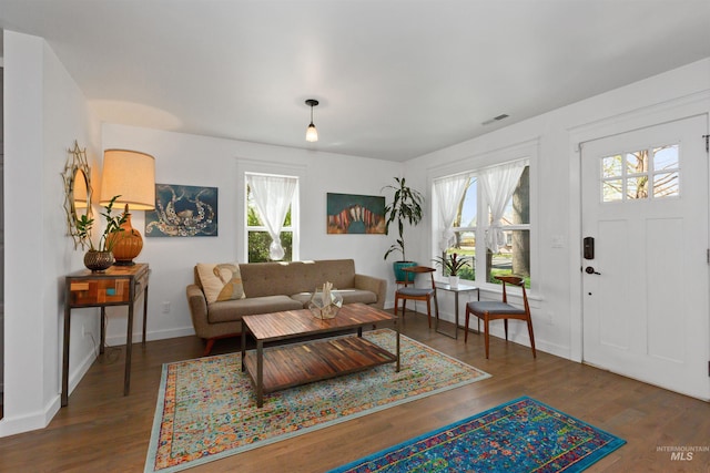 living room with baseboards, visible vents, and wood finished floors