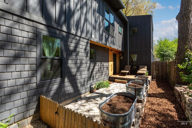 view of side of property with board and batten siding and fence