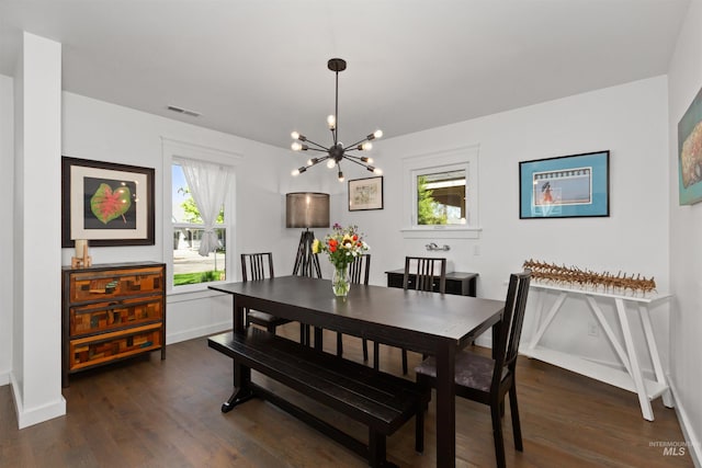 dining room with dark wood-type flooring, a notable chandelier, and a healthy amount of sunlight