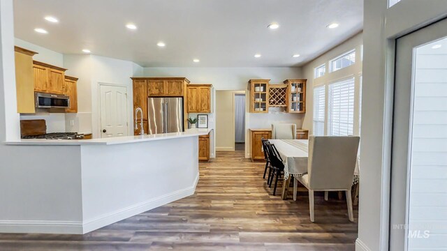 104 E Stonewater, Eagle, ID 83616 - kitchen featuring appliances with stainless steel finishes, wood finished floors, glass insert cabinets, brown cabinetry, and recessed lighting