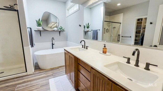 104 E Stonewater, Eagle, ID 83616 - bathroom featuring a shower stall, a freestanding tub, wood finished floors, a walk in closet, and double vanity