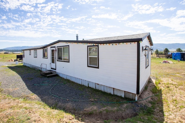 view of side of home featuring a mountain view and a lawn