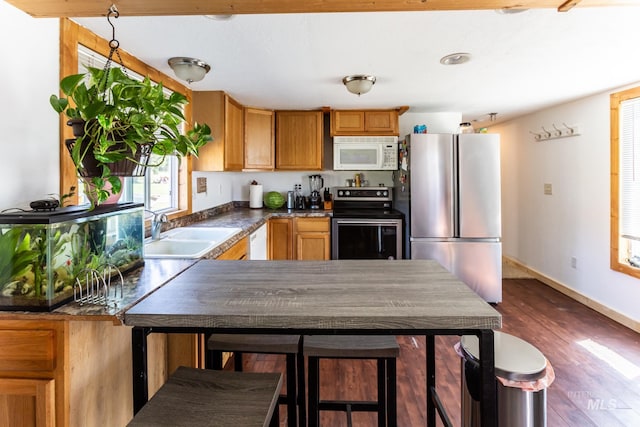 kitchen featuring sink, kitchen peninsula, stainless steel appliances, and dark hardwood / wood-style flooring