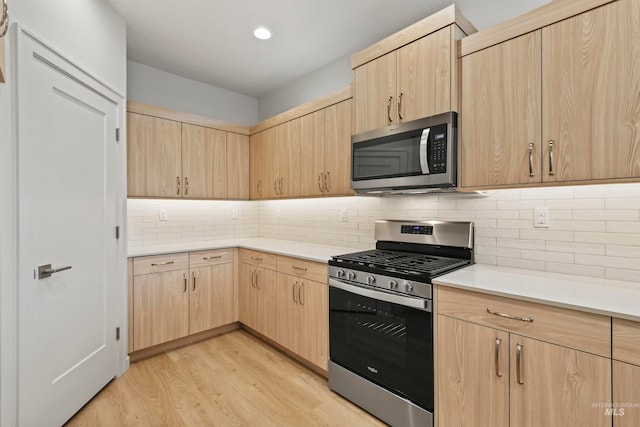 kitchen featuring light brown cabinetry, appliances with stainless steel finishes, light hardwood / wood-style flooring, and tasteful backsplash