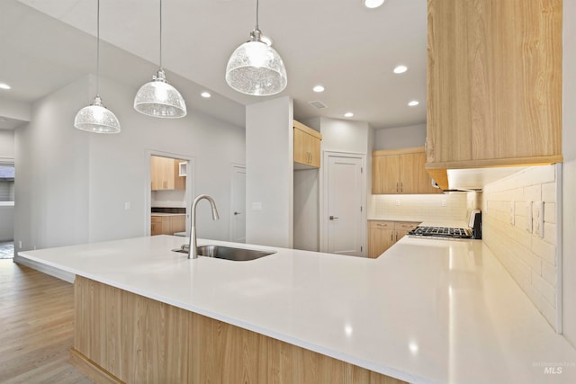 kitchen featuring light hardwood / wood-style floors, kitchen peninsula, sink, and hanging light fixtures