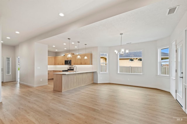 kitchen with stainless steel appliances, light brown cabinetry, light hardwood / wood-style flooring, and pendant lighting