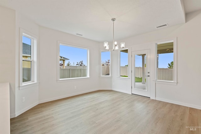 unfurnished dining area with a chandelier and light hardwood / wood-style flooring