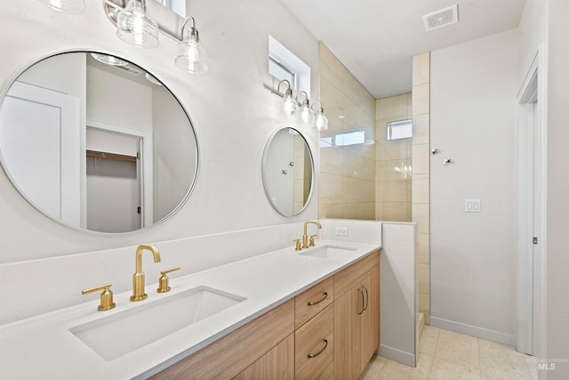 bathroom with vanity, tile patterned flooring, and tiled shower