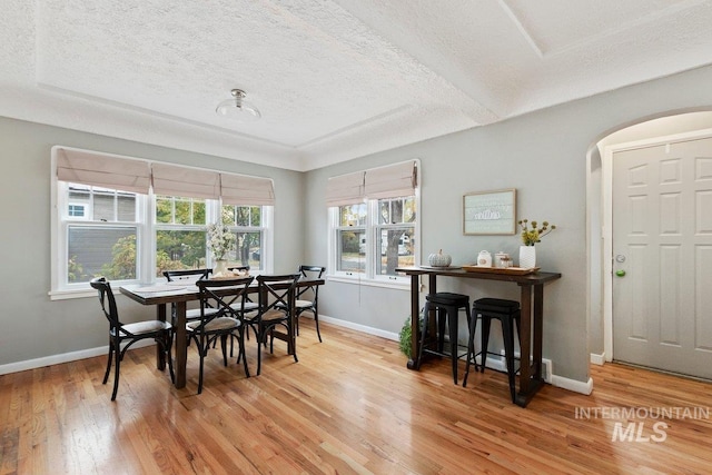 dining space with light wood-type flooring and a textured ceiling