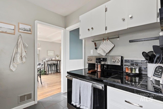 kitchen with white cabinetry, stainless steel range with electric stovetop, and dark hardwood / wood-style flooring