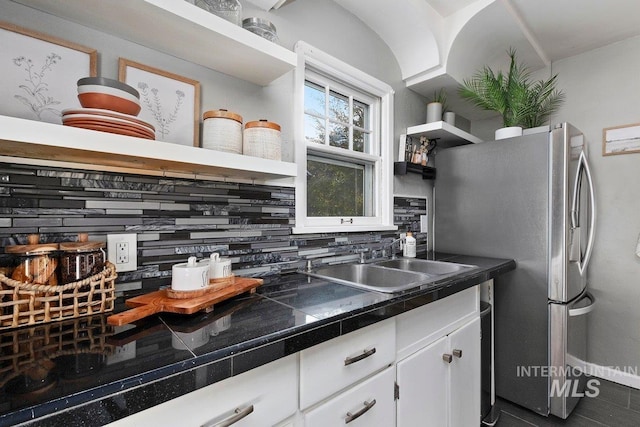 kitchen featuring stainless steel refrigerator, white cabinetry, sink, and decorative backsplash