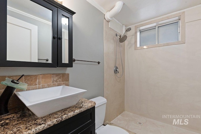 bathroom featuring toilet, vanity, tiled shower, and crown molding