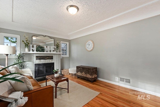 living room with a textured ceiling, a fireplace, hardwood / wood-style floors, and plenty of natural light