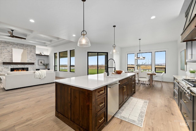 kitchen featuring decorative light fixtures, a fireplace, plenty of natural light, and an island with sink