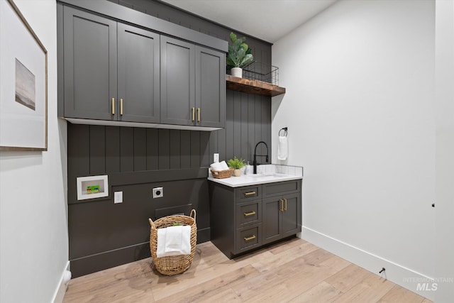 clothes washing area featuring sink, cabinets, washer hookup, electric dryer hookup, and light hardwood / wood-style flooring