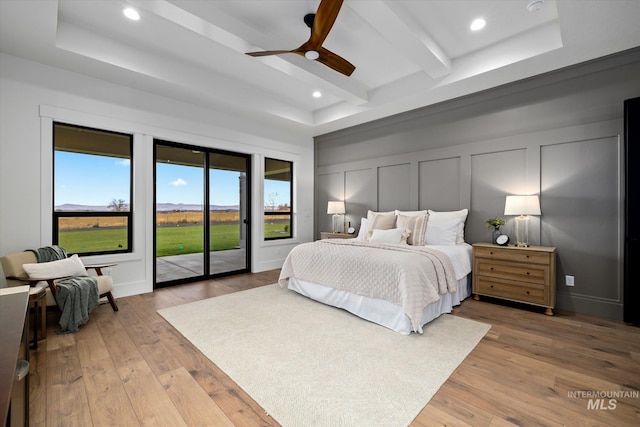 bedroom with ceiling fan, light hardwood / wood-style floors, beam ceiling, and access to outside