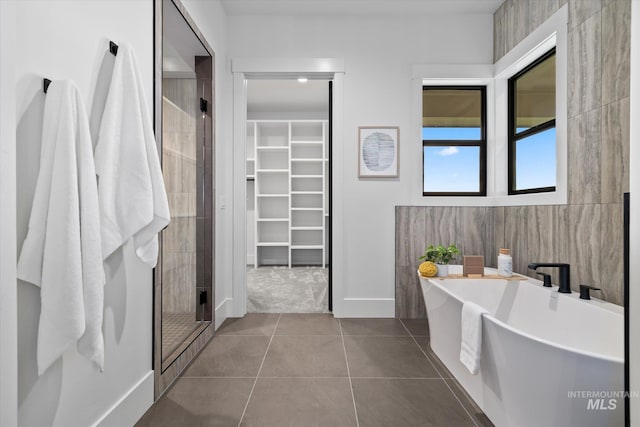 bathroom with separate shower and tub, tile patterned flooring, and tile walls