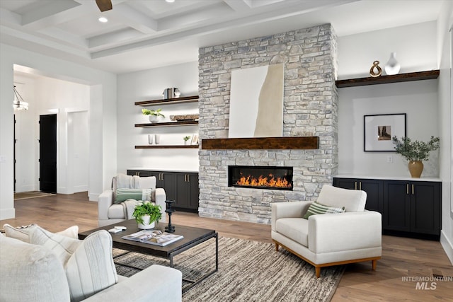 living room with beamed ceiling, wood-type flooring, a fireplace, and coffered ceiling