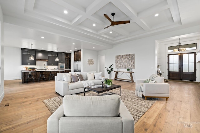 living room featuring french doors, beamed ceiling, light hardwood / wood-style floors, and coffered ceiling