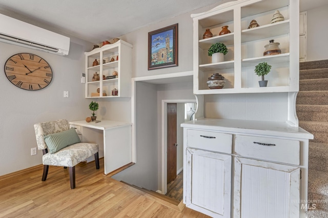 interior space featuring white cabinetry, a wall mounted AC, and light hardwood / wood-style flooring