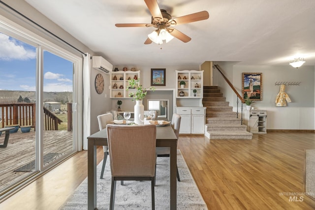 dining space featuring a wall mounted AC, ceiling fan, and light hardwood / wood-style flooring